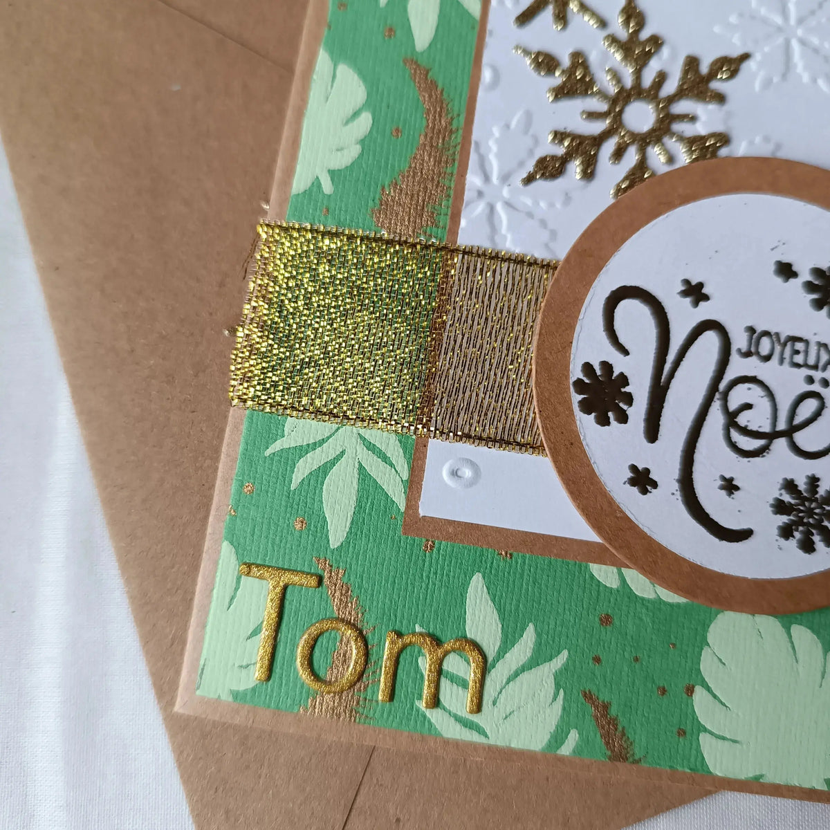 Détail de l'étiquette embossée Joyeux Noël sur la carte Douce Forêt