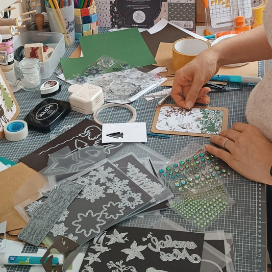 zoom sur les mains de l'artisane qui crée des cartes de noël - l'atelier de lili lasouris
