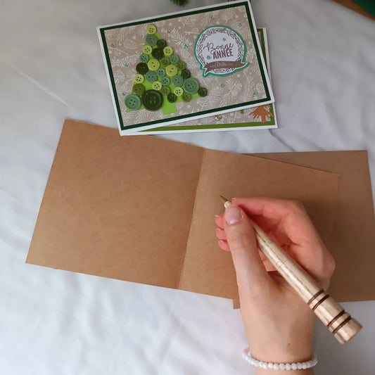 une main qui tiens un stylo prête à écrire ses voeux de fin d'année sur une carte artisanale