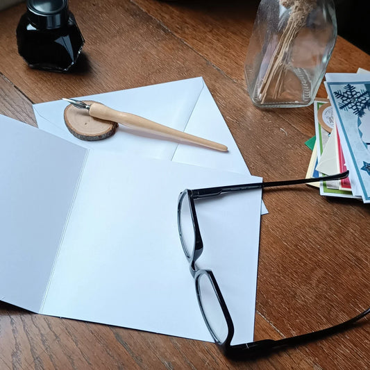 carte ouverte avec une paire de lunette et une plume pour écrire des cartes de bonne année