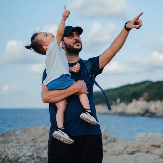 un enfant dans les bras de son papa en train d'observer