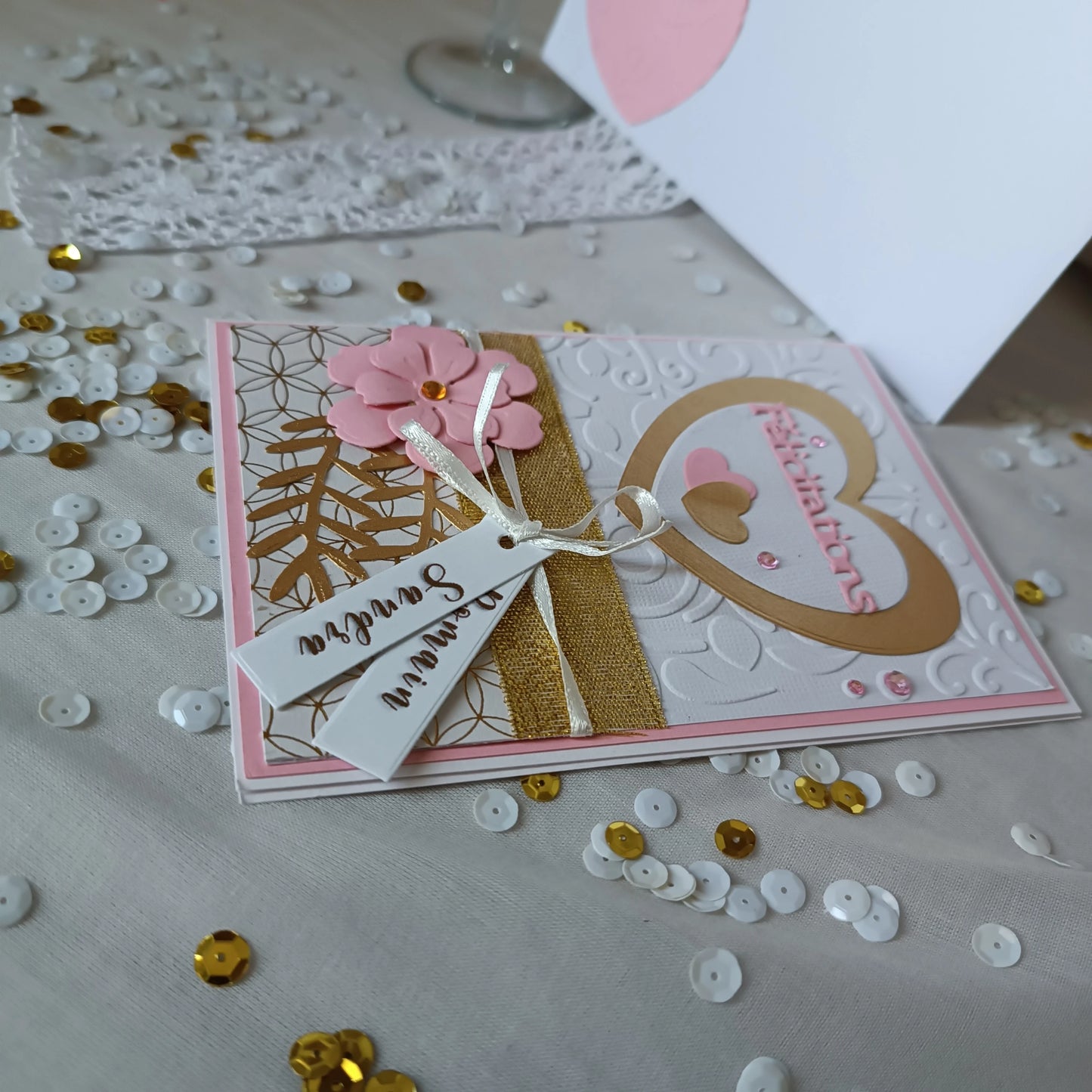 Détail du papier blanc embosse à motif baroque sur la carte de mariage rose et or