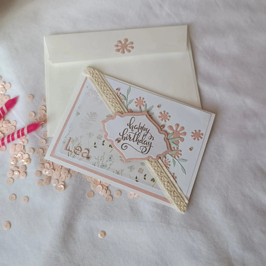 Carte anniversaire fleurs pastel présentée avec son enveloppe