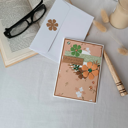 Carte de départ collègue abricot et vert sauge posée sur son enveloppe, avec livre ancien, lunettes et bougie