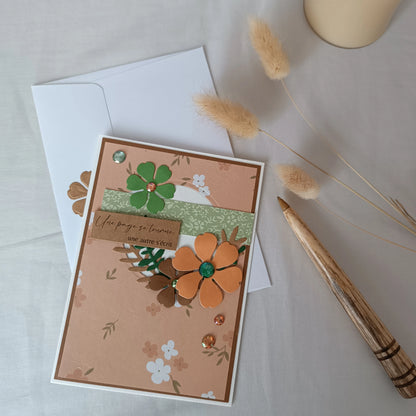 Carte de départ collègue abricot et vert sauge posée sur son enveloppe, avec brins d'herbes séchées
