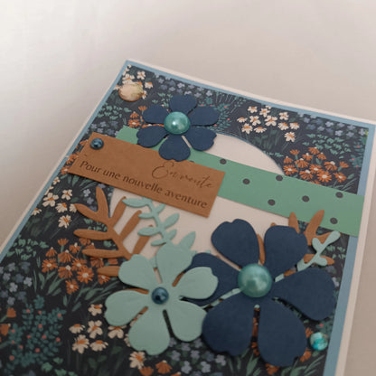 Détail des fleurs découpées à la main et de l'étiquette kraft « En route pour une nouvelle aventure »