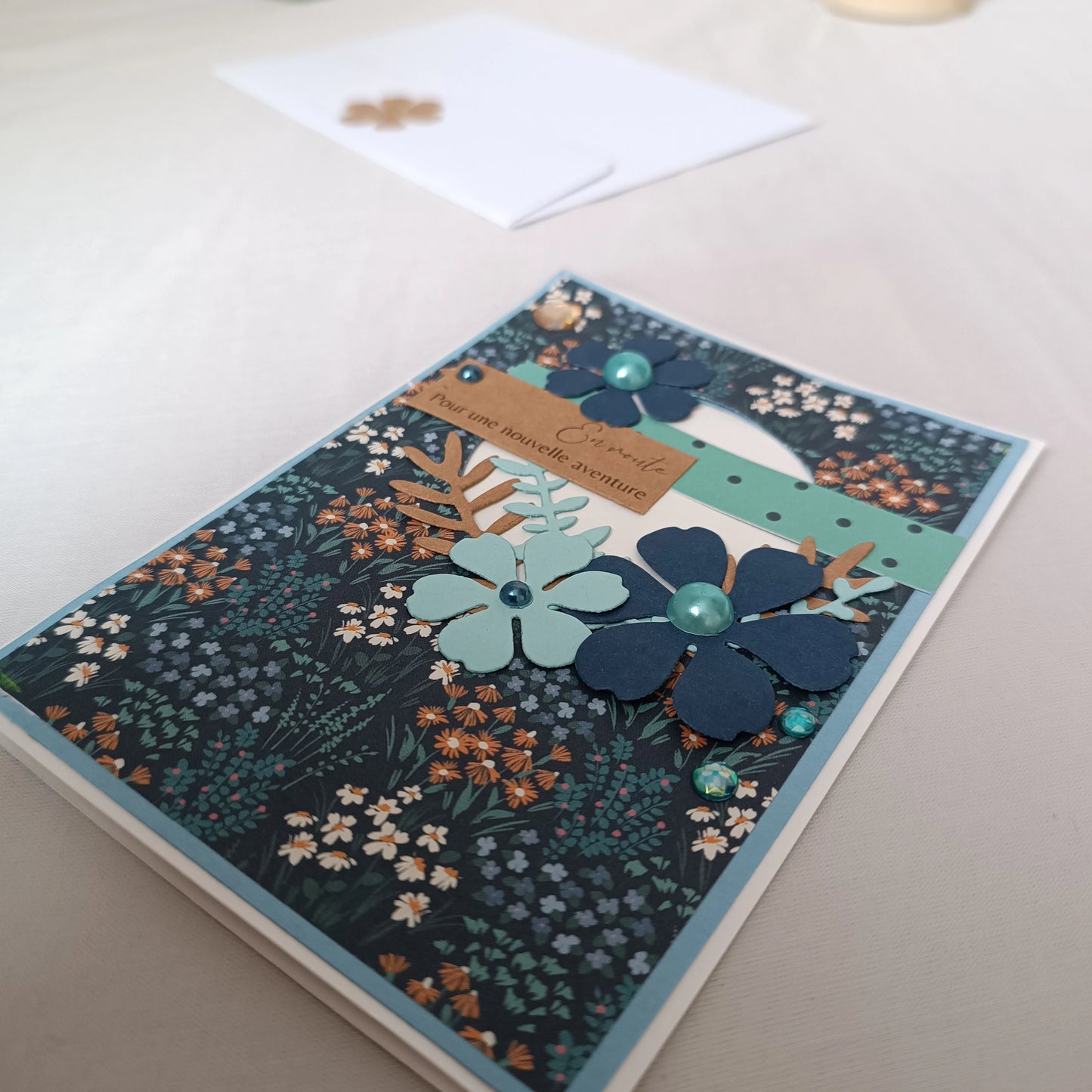 Gros plan sur les fleurs bleu marine et bleu clair ornées de perles, sur fond de prairie fleurie