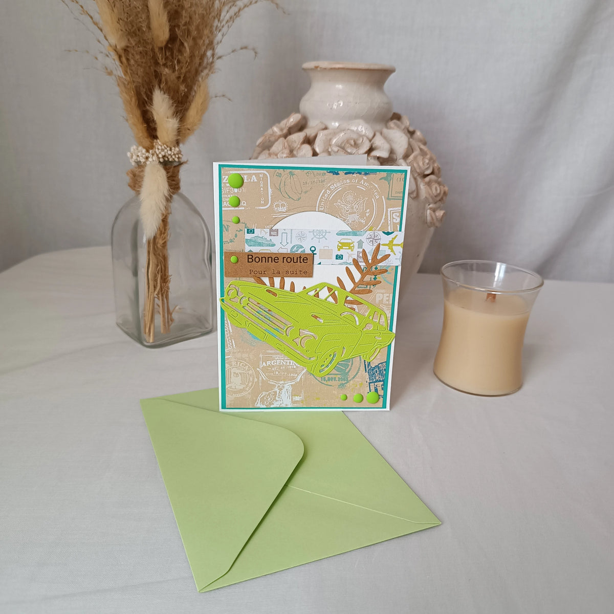 Carte de départ homme voiture vert anis tenue debout devant un vase en céramique et une bougie, ambiance cosy